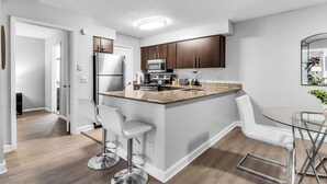 A modern kitchen with a central island, stainless steel appliances, and white bar stools. - Walk to Las Olas + 15 Min to Beach + Sleeps 6 (Fort Lauderdale)