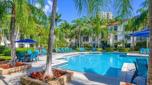 A pool area with lounge chairs, palm trees, and a clear blue sky. - Walk to Las Olas + 15 Min to Beach + Sleeps 6 (Fort Lauderdale)