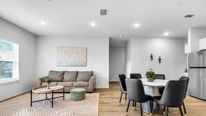 Una sala de estar moderna con un sofá, una mesa de centro y un comedor con sillas.