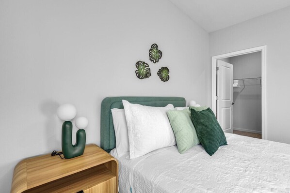 Een slaapkamer met een bed, nachtkastje en een deur naar een inloopkast.