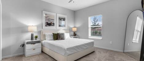 A bedroom with a bed, two bedside tables, a ceiling fan, and a window with blinds.