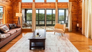 Ein geräumiger Loft mit hohen Decken, einer großen Lüster, einem Sofa, einem Couchtisch und Blick ins Freie.