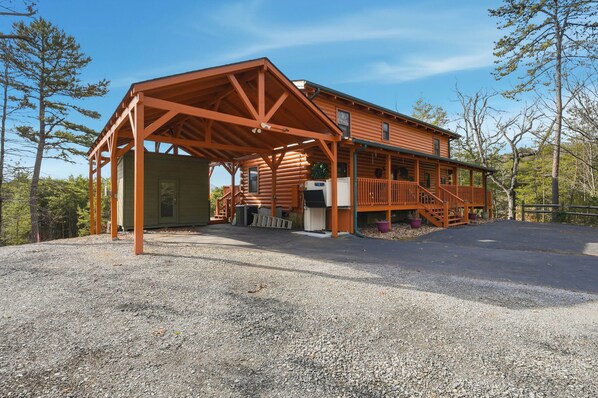 A log cabin with an open porch and a covered area, surrounded by trees. - Mountain View Cabin with Fire Pit & Entertainment (Sevierville)