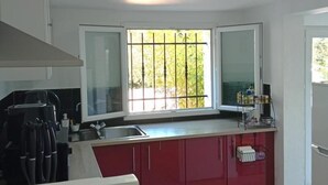 Una cocina moderna con un amplio ventanal, una cafetera y una isla roja.