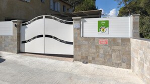 Una entrada protegida por un portón con un cartel de GITE Var, un letrero de propiedad privada y un muro de piedra.