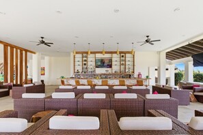 A spacious lounge area with multiple seating options, a bar with a television, and ceiling fans. - https://169666_1.holidayfuture.com/ (Bajos de Chila)