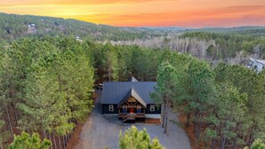 Eine Lodge mit einer zentralen Terrasse, umgeben von dichtem Wald, bei Sonnenuntergang.