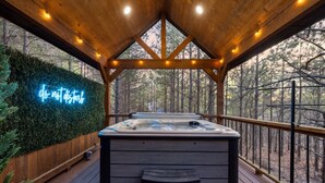 Eine Holzterrasse mit Whirlpool, einer Neonreklame und einem Hollerleger.