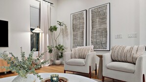 A modern living room with a white sofa, a coffee table with decorative items, and two abstract wall art pieces. - Luxury Resort Oasis : Pool, Pickleball, Sauna, Spa,     Sleeps 14 Comfortably  (Phoenix)