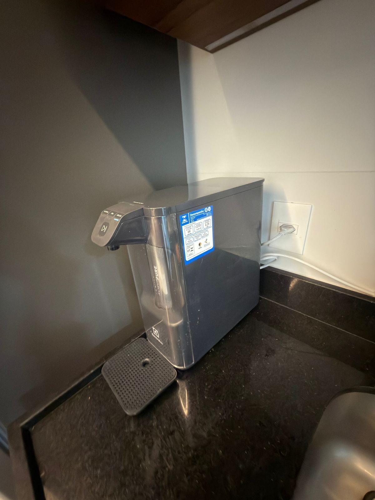 A coffee machine with a digital display, a power outlet, and a black countertop.