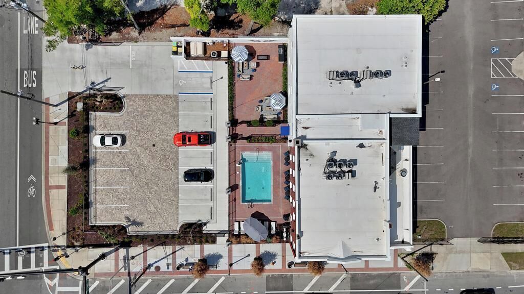Vista aérea de um estacionamento com piscina, área coberta com guarda-sóis e um edifício com a inscrição 'La Jolla'.