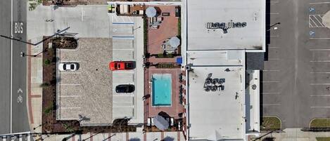 Vista aérea de um estacionamento com piscina, área coberta com guarda-sóis e um edifício com a inscrição 'La Jolla'.