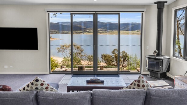 Una sala de estar con un amplio ventanal corredera, chimenea, televisor de pantalla plana y sofá.