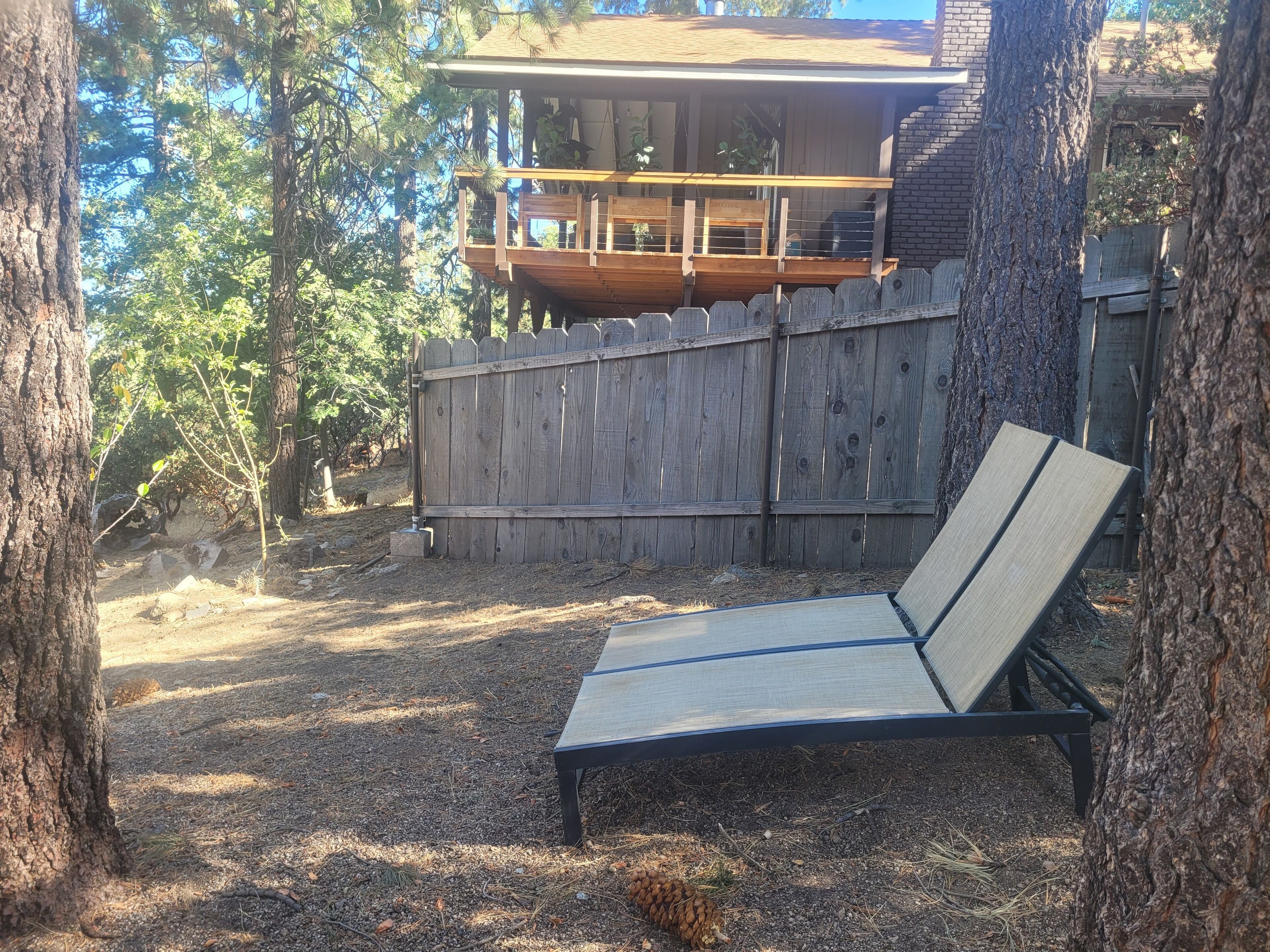 A wooden deck with a bench, surrounded by trees and a wooden fence.