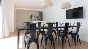 A dining area with a black table and chairs, a flat-screen TV mounted on the wall, and a kitchen in the background. - MOT Rentals + Guatemala D - 2 Bd in Palermo Soho (Buenos Aires)