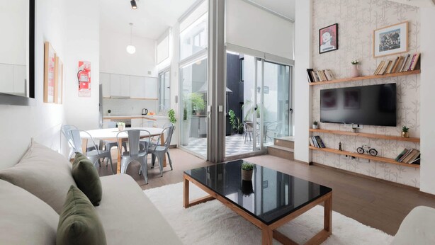 A modern living room with a sofa, coffee table, TV, and a dining area with chairs and a table. - MOT Rentals + SantaFe 5164 - 3 Bd Pool & BBQ Palermo Hollywood (Buenos Aires)