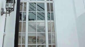 Een wit gebouw met een groot raam bestaande uit meerdere ruiten en een zwart luifel.