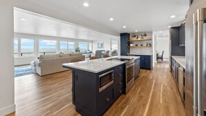 A modern kitchen with a large island, wooden flooring, and built-in appliances. - Hot tub on the Beach with Super-Fast Wi-Fi (Oak Harbor)