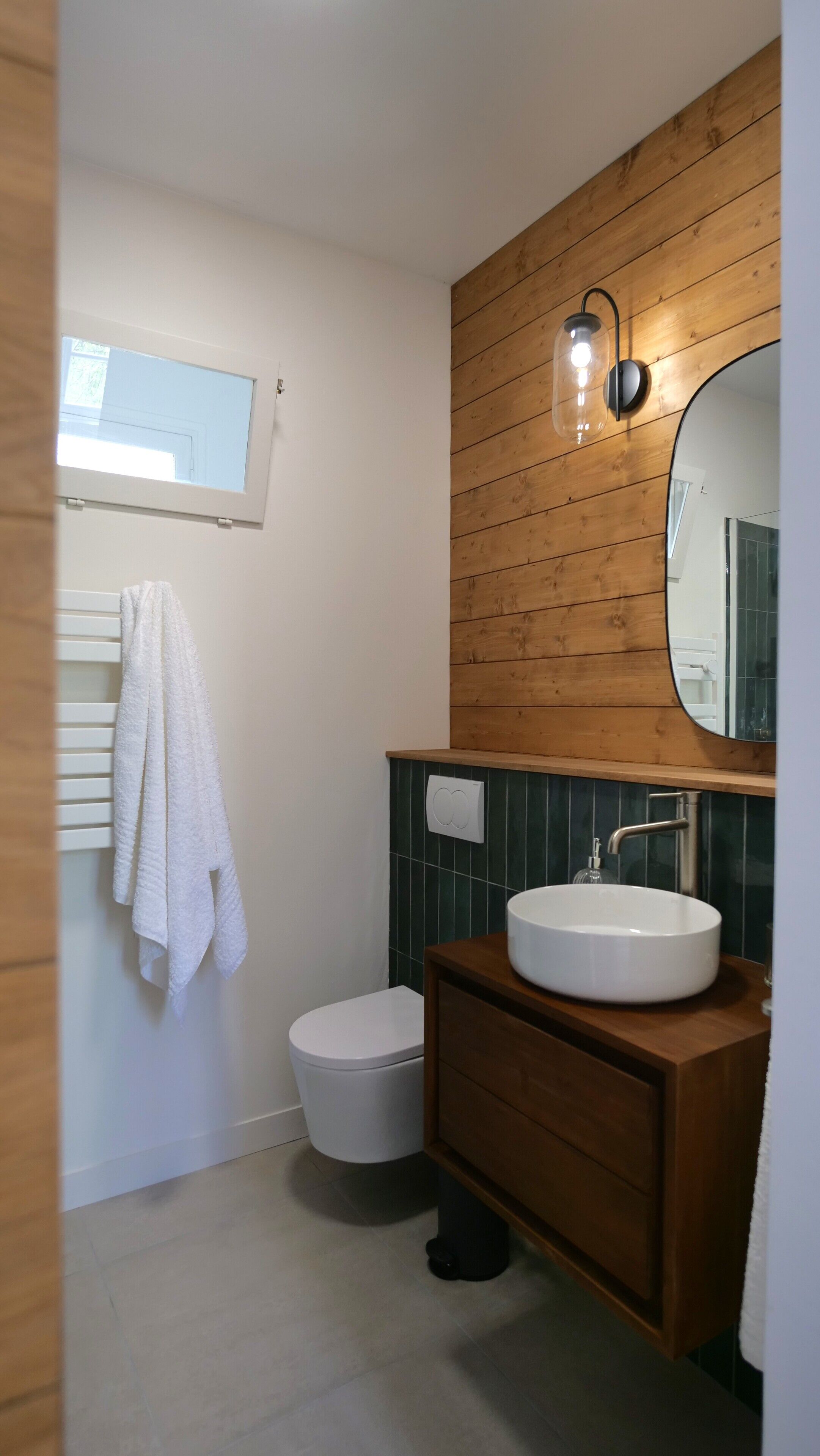 A modern bathroom with a wooden vanity, a white sink, and a toilet.