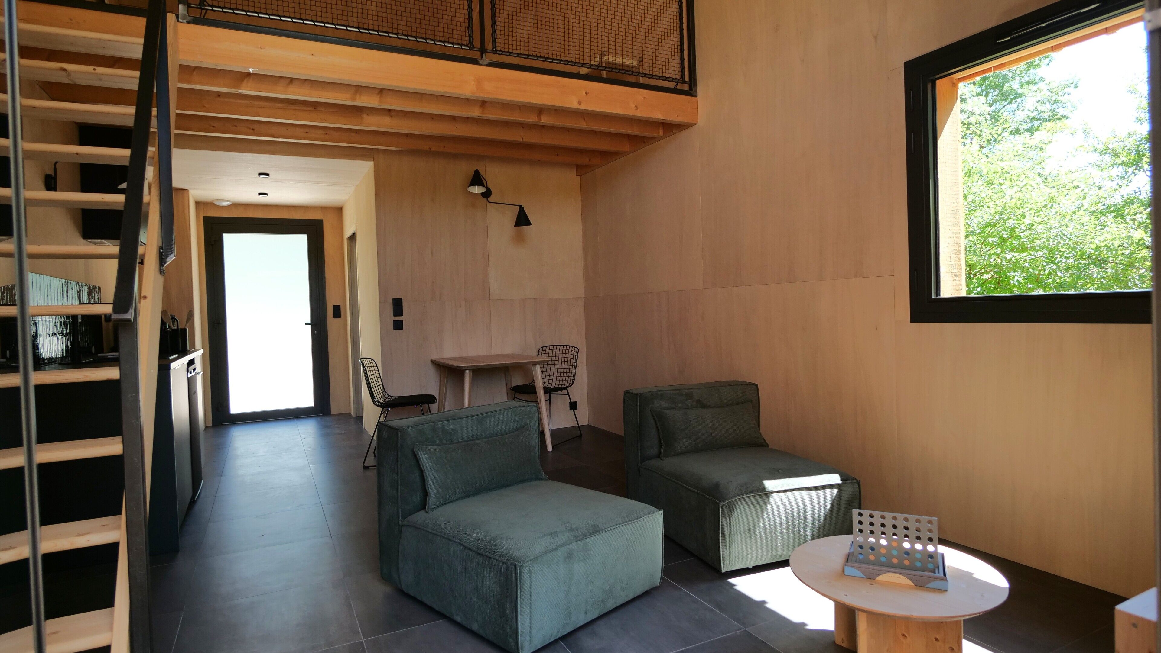 Un interior moderno con techo estilo loft, un comedor con mesa y sillas, y una zona de estar con dos sofás y una mesita redonda.