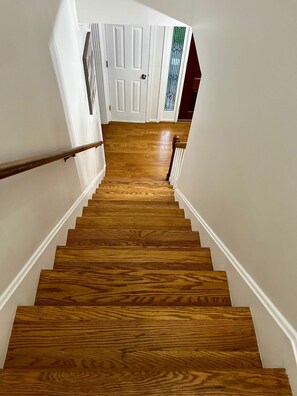 A wooden staircase with white walls and a door at the top. - Spacious 4-bedroom house in a prized location in  Louisville (Louisville)