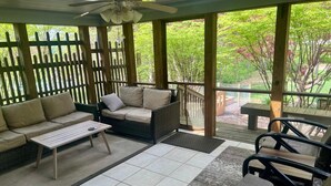 Ein überdachter Patio-Bereich mit einer Couch, Stühlen und einem Tisch.