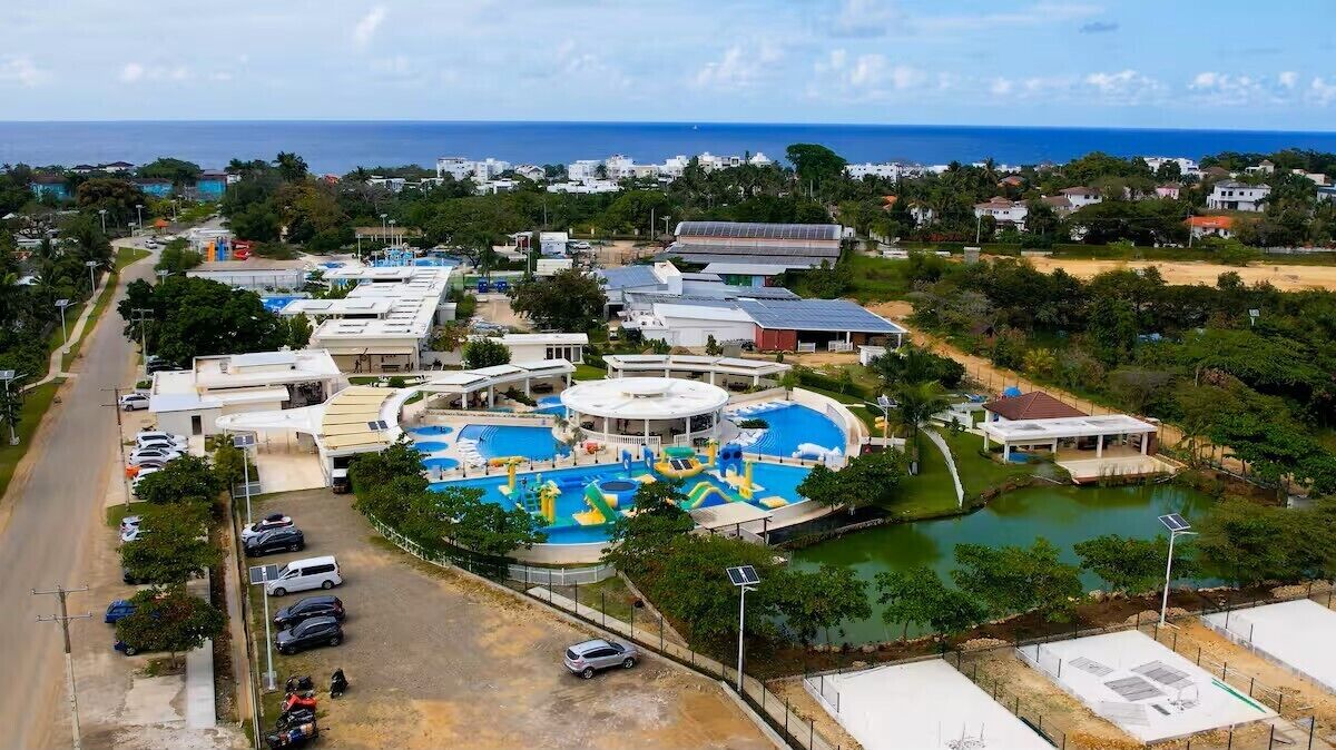 Vista aérea de um resort com várias piscinas, área de estacionamento e vista para o oceano.