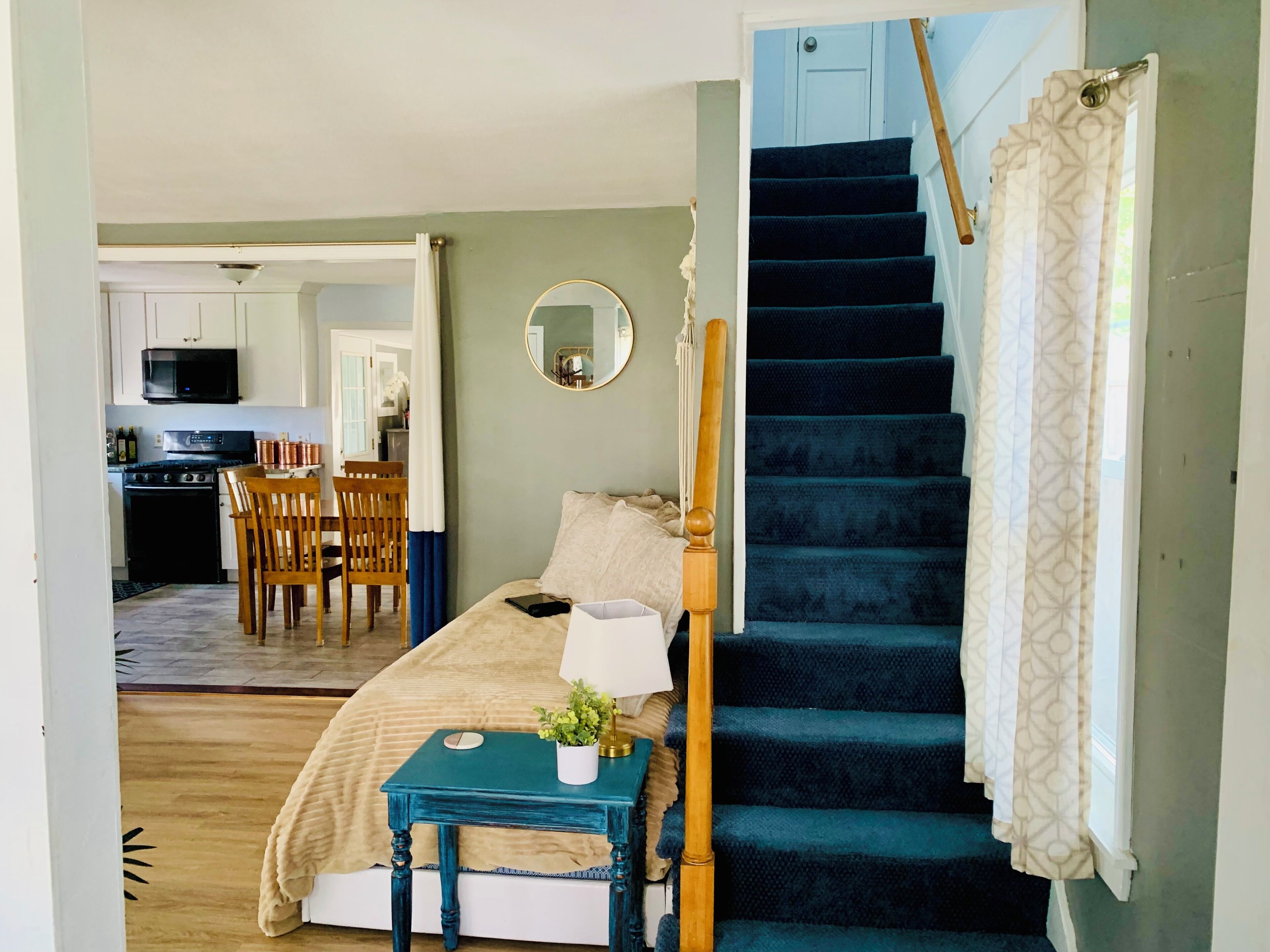 Une chambre à coucher comprenant un lit, une table de chevet et donnant sur une cuisine et un coin repas.