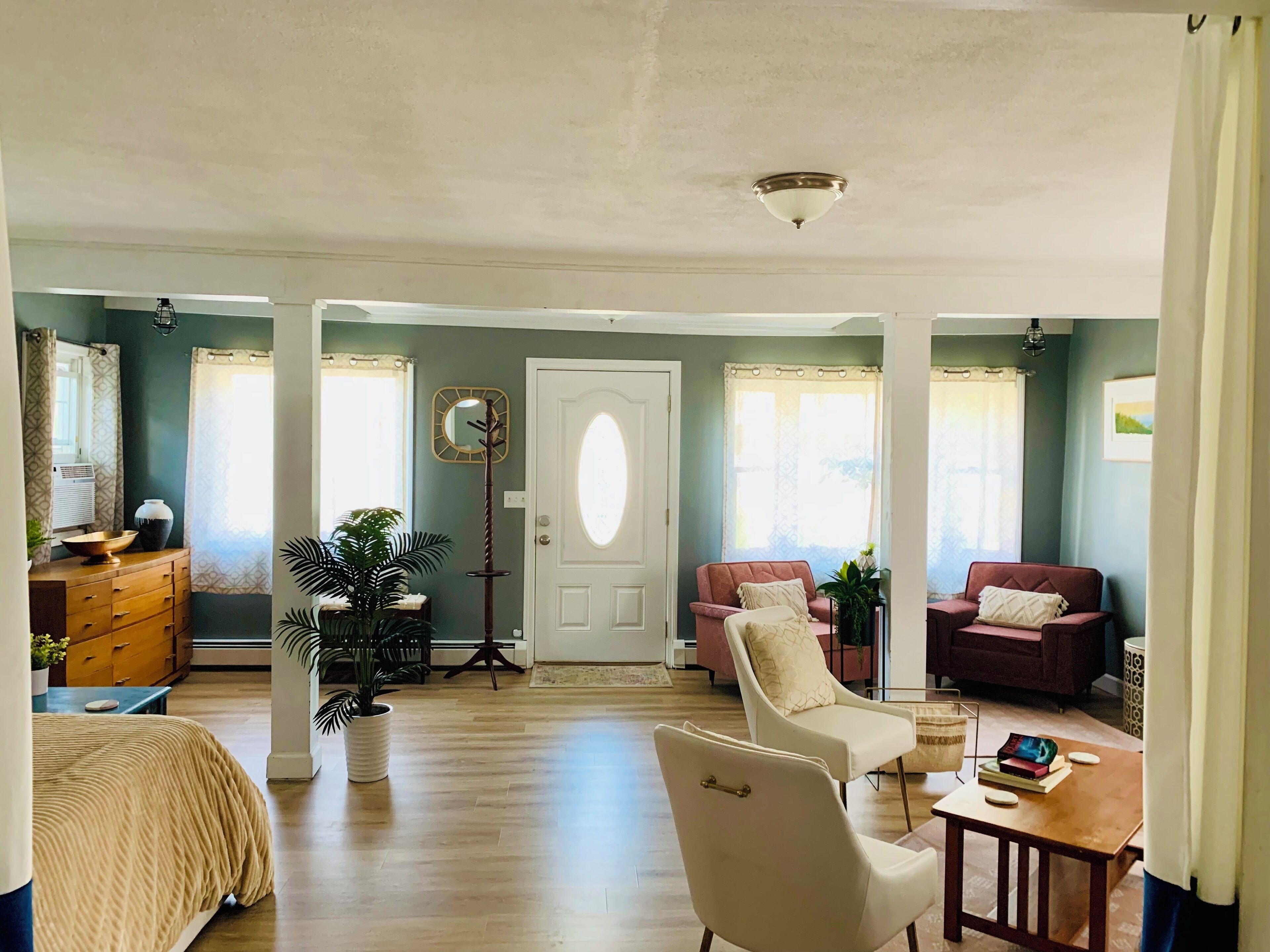 A spacious living room with a large window, a door, and a seating area with two sofas and a chair.
