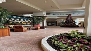 Un amplio hall con un gran árbol de Navidad, zonas de estar y diversas plantas.
