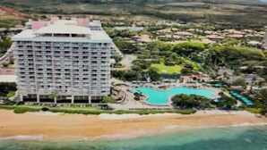 Un hotel grande con varios pisos, piscina y playa.