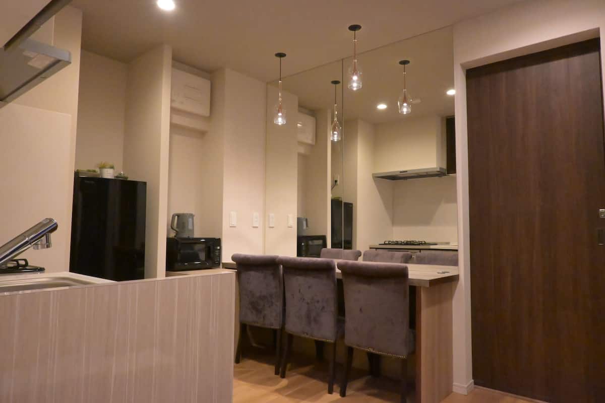 Una cucina moderna con zona pranzo, caratterizzata da lampade a sospensione, forno a microonde integrato e una porta in legno scuro.