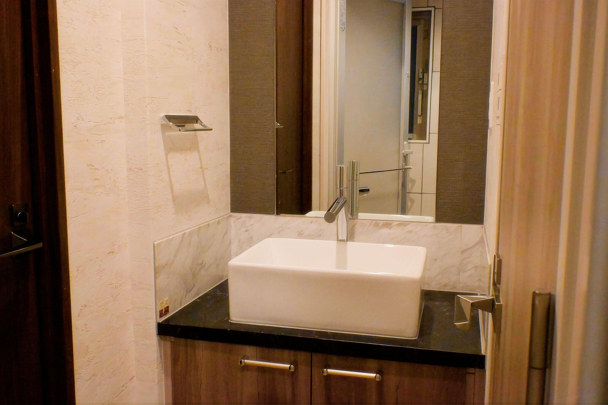 A bathroom with a white sink, dark countertop, and wooden cabinets.