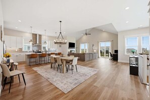 A spacious kitchen with a dining area, a living room, and a large sliding glass door leading to a balcony. - 5682 - Beers and Sunshine a Oceanside 5BR home in Nags Head, perfect for families and beach lovers! (Nags Head)