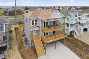 A two-story house with a balcony, a front porch, and a driveway. - 5682 - Beers and Sunshine a Oceanside 5BR home in Nags Head, perfect for families and beach lovers! (Nags Head)