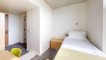 Een slaapkamer met een bed, nachtkastje en een stoel.
