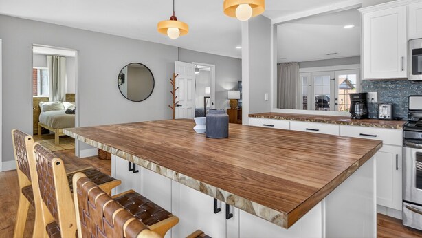 A modern kitchen with a central island, white cabinetry, and pendant lighting. - Stylish 6BR Home, Pool, Sleeps 12,Near Old Town (Scottsdale)