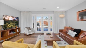 A living room with a television, sofa, chairs, and a coffee table. - Stylish 6BR Home, Pool, Sleeps 12,Near Old Town (Scottsdale)
