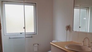 Een badkamer met toilet, wastafel, spiegel en een raam.