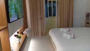 A hotel room with a bed, a TV mounted on the wall, a bedside table with a vase of flowers, and a window with curtains. - Accommodation marrakech guéliz (Marrakech)