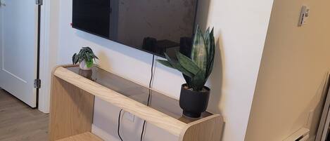A TV mounted on a wall with a wooden console below it.