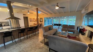 A spacious living area with a kitchen, bar seating, and a fireplace. - Private Home on Canal w/ Heated Pool, Walk to Siesta Key Beach & Village (Siesta Key)
