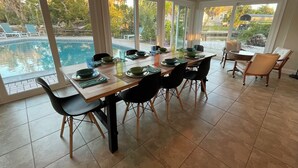 A dining area with a view of a swimming pool, large windows, and a ceiling fan. - Private Home on Canal w/ Heated Pool, Walk to Siesta Key Beach & Village (Siesta Key)