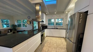 A modern kitchen with a large island, stainless steel appliances, and a skylight. - Private Home on Canal w/ Heated Pool, Walk to Siesta Key Beach & Village (Siesta Key)
