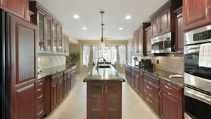 A spacious kitchen with dark wood cabinets, stainless steel appliances, and a central island.