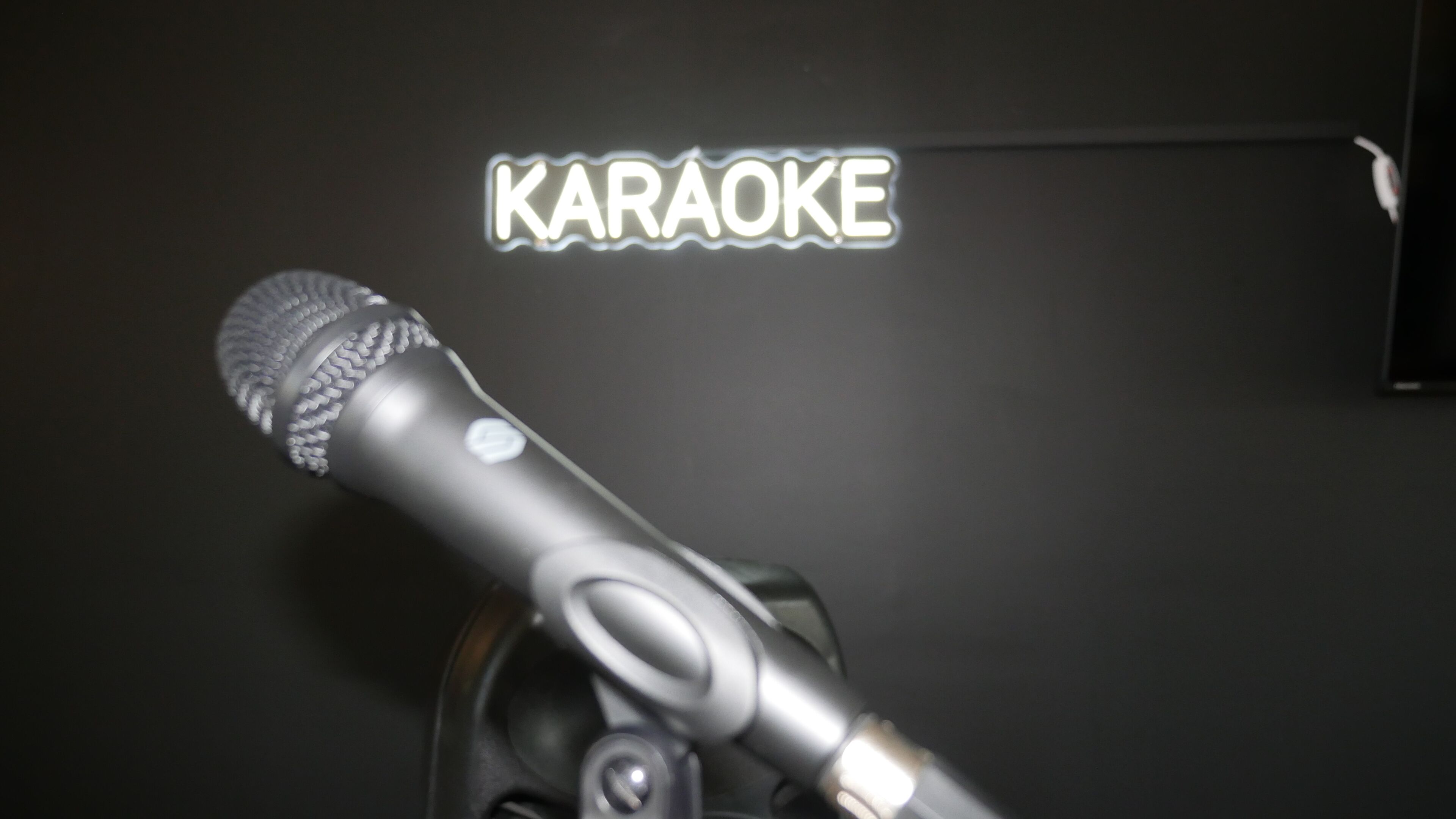 A microphone with a neon sign reading "KARAOKE" in the background.