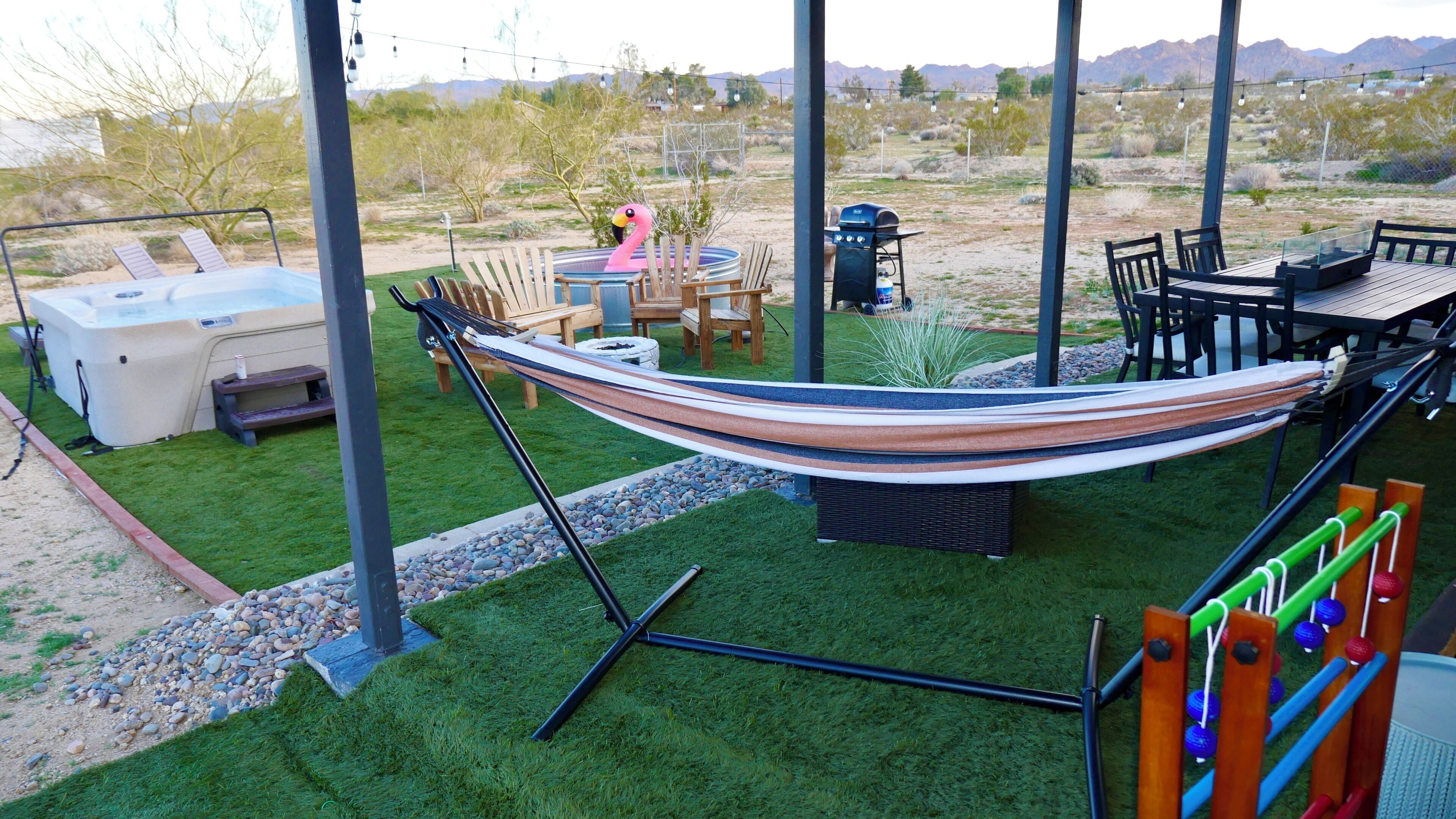 Una hamaca, mobiliario exterior, un jacuzzi y una parrilla de barbacoa en un jardín.