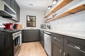 Eine moderne Küche mit dunklen Schränken, weißen Arbeitsplatten und Holzbalken.