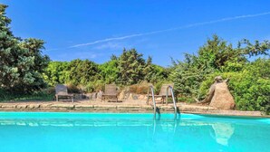 A clear blue pool with wooden lounge chairs and a stone sculpture. - Holiday Apartment Sea of Juniper Two-Room Apartment (Badesi)