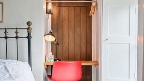 A bedroom with a bed, a desk with a chair, a nightstand, a lamp, and a wooden door. - Quiet alternative to a hotel - Furzen Farmhouse (Gloucestershire)